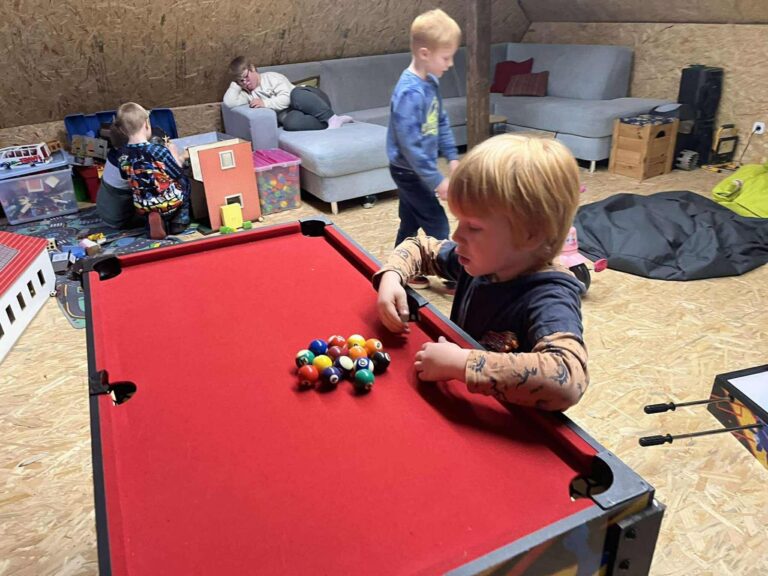 Kleinkind spielt an einem kleinen roten Billardtisch in der Spielecke