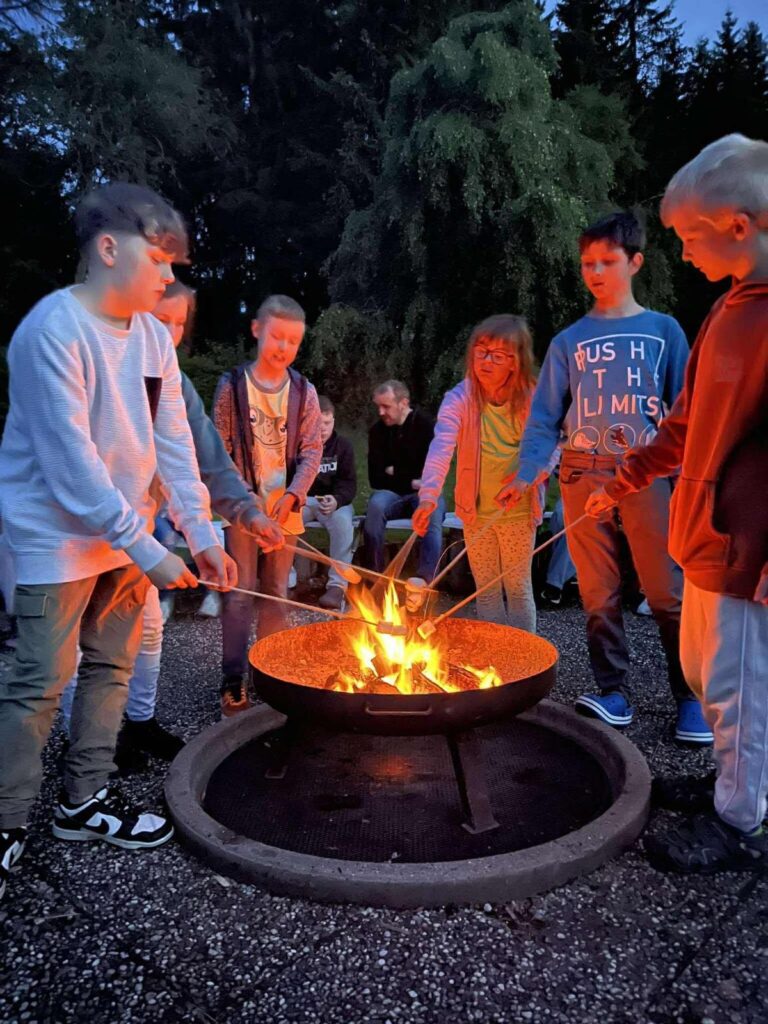 Jugendliche grillen abends Stockbrot über dem Lagerfeuer