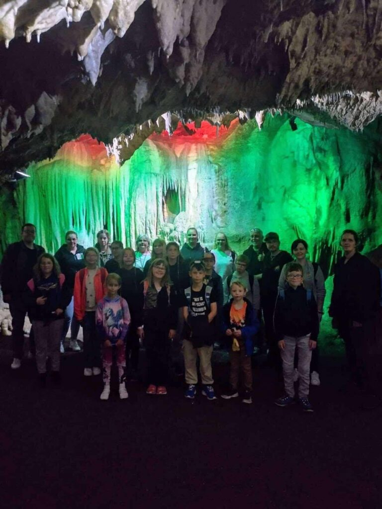 Gruppenfoto der Kinder- und Jugendfreizeit in einer grün beleuchteten Höhle