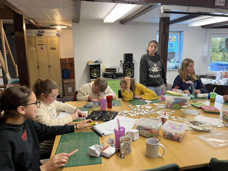 Kinder basteln konzentriert an einem Tisch im Gemeinschaftsraum des Haus Kunterbunt