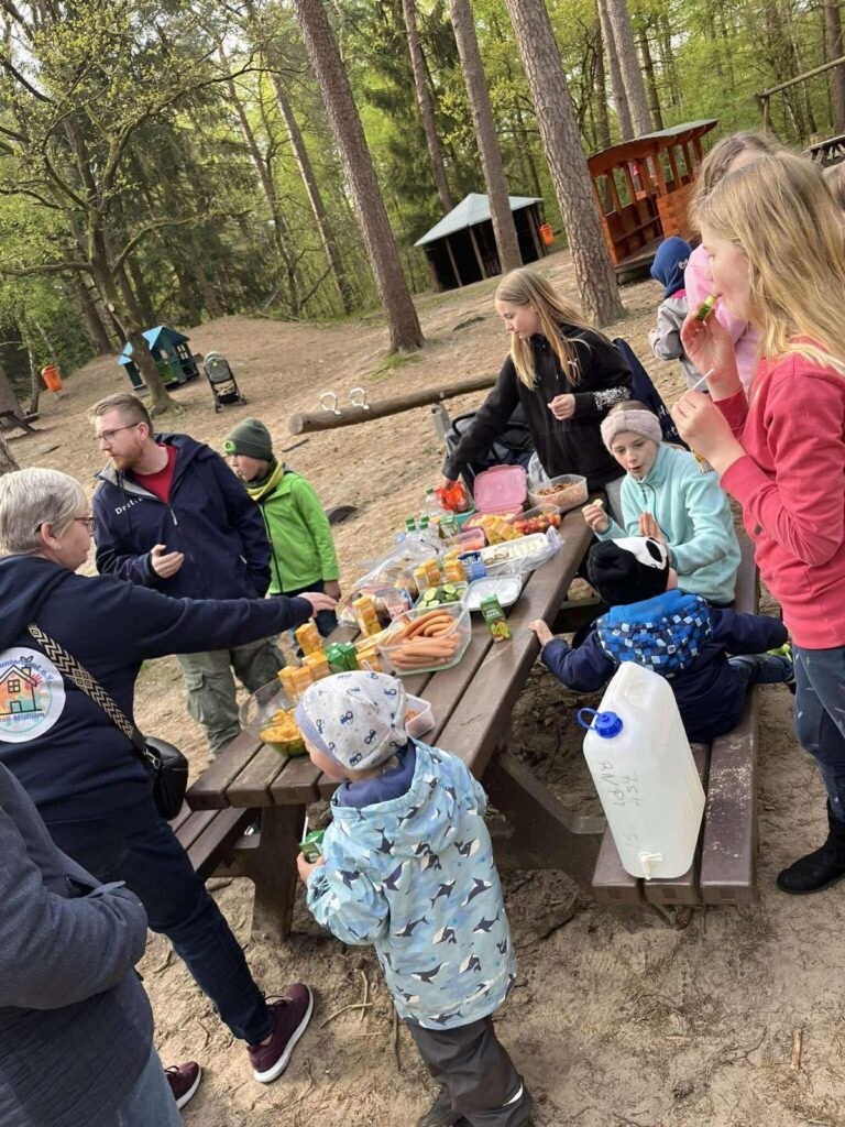 Große Runde beim gemeinsamen Essen an Biertischen im Freien