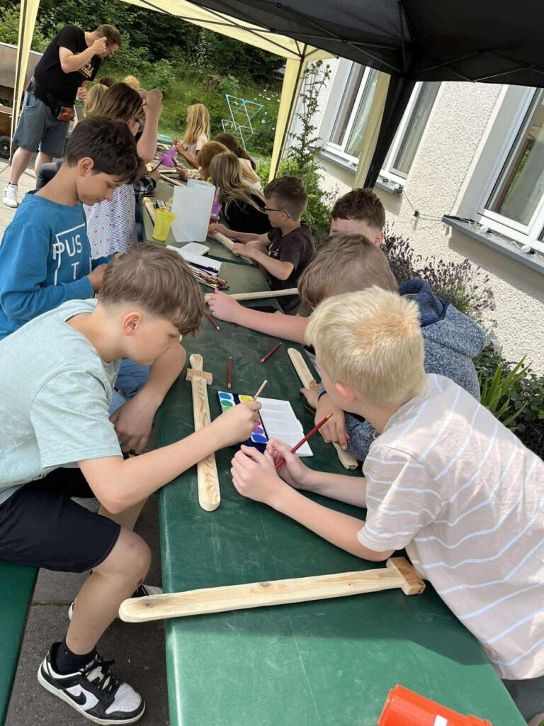 Jungen basteln gemeinsam mit Holzstäbchen am Tisch